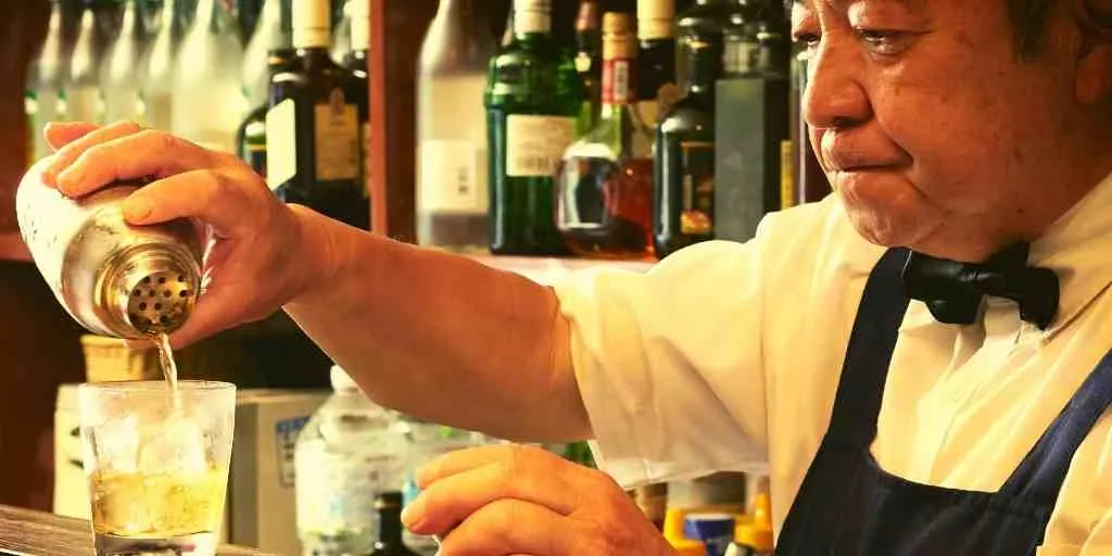 older man pouring drink from shaker.